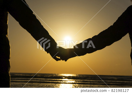 父母和孩子手牽手在沙灘上看日落 82198127