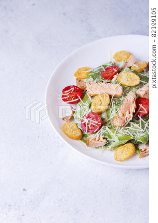 Caesar salad with red fish (salmon, trout), cherry tomatoes, croutons, parmesan cheese and romaine. Traditional American dish. Copy space. Close-up, selective focus. 82199105
