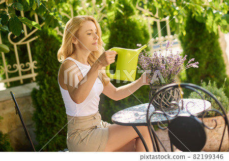 Pensive woman with watering can near flowerpot Pensive woman with watering can near flowerpot 82199346