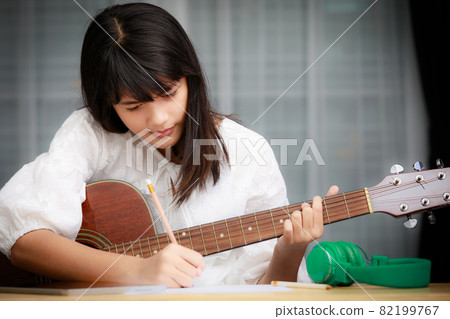 Young girl playing guitar and compose music 82199767