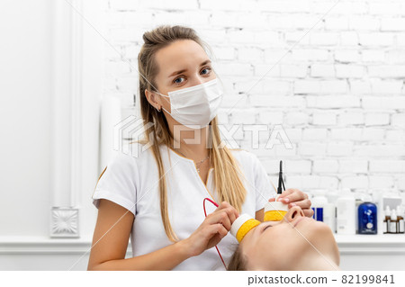 Young adult attractive professional beautician doctor portrait in protective face mask do facial care and treatment procedure to female client. Health safety therapy. Beauty salon new normal covid-19 Young adult attractive professional beautician doctor portrait in protective face mask do facial care and treatment procedure to female client. Health safety therapy. Beauty salon new normal covid-19 82199841