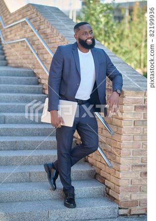 A picture of a dark-skinned man in a suit with a laptop A picture of a dark-skinned man in a suit with a laptop 82199936