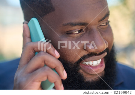 A dark-skinned man in a suit with a phone in hands 82199942