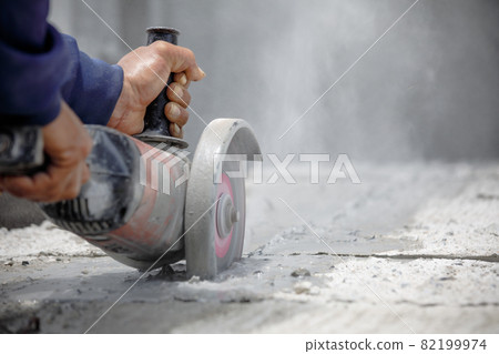 Worker using tool to cut concrete floor 82199974