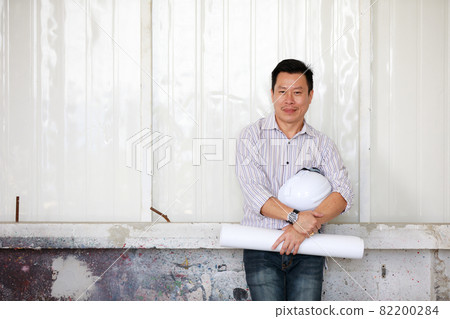 Portrait of male engineer with self-confidense and friendly manner, holding roll paper in hand Portrait of male engineer with self-confidense and friendly manner, holding roll paper in hand 82200284