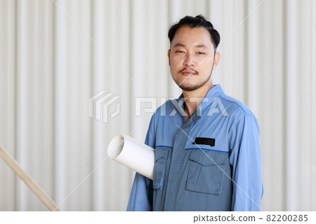 Portrait of male engineer with self-confidense and friendly manner, holding roll paper in hand Portrait of male engineer with self-confidense and friendly manner, holding roll paper in hand 82200285