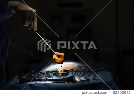 Doctor use medical instrument to catch the gauze that soaked and wet blood with drop in surgery room. 82200972