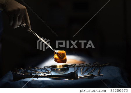 Doctor use medical instrument to catch the gauze that soaked and wet blood  in surgery room. 82200973
