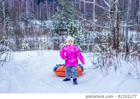 Little girl drags slide-slide cheesecake up snowy hill. Little girl drags slide-slide cheesecake up snowy hill. 82201277