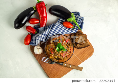 popular vegetable dish of world cuisine in a glass bowl top view - Ajapsandali, Pinjur, stewed vegetables, eggplant caviar. Main ingredients: eggplants, tomatoes, bell peppers, garlic, spices. 82202351