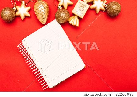 Gold Christmas balls and toys with empty blank note sheet on a red background Gold Christmas balls and toys with empty blank note sheet on a red background 82203083