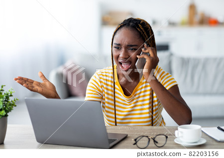 Nervous black woman working from home, fighting on phone 82203156