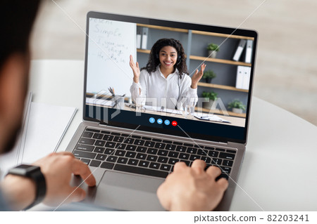 Friendly millennial afro american lady teacher explains rules to young caucasian male on laptop screen at home 82203241