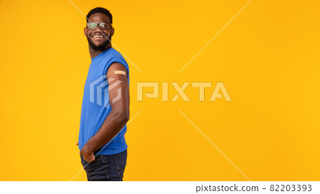Black Male Showing Vaccinated Arm After Shot On Yellow Background Black Male Showing Vaccinated Arm After Shot On Yellow Background 82203393