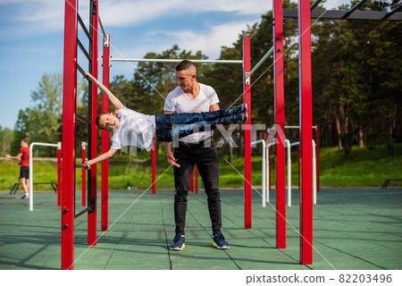 Caucasian man teaching boy to make a flag on the playground. Caucasian man teaching boy to make a flag on the playground. 82203496