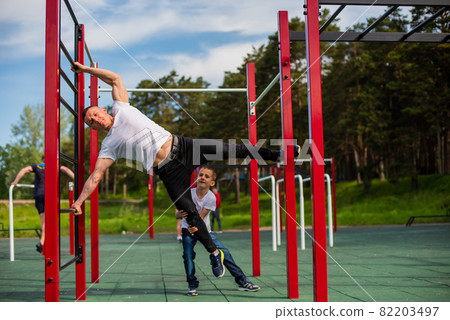 Caucasian man teaching boy to make a flag on the playground. Caucasian man teaching boy to make a flag on the playground. 82203497