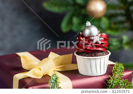 Tasty homemade festive Christmas muffin or cupcake with cream and sweet balls and snowflakes 82203872
