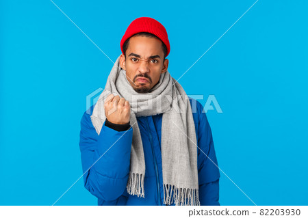 Angry, mad guy threatening person shaking fist at someone on streets. Outraged pissed-off african american man saying i will show you, frowning grimacing and warning you, blue background 82203930
