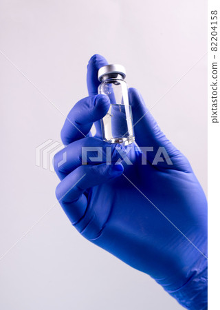 Vaccination from coronavirus Covid-19 concept with doctor's hands wearin protective gloves, holding botle of liquid medication. 82204158