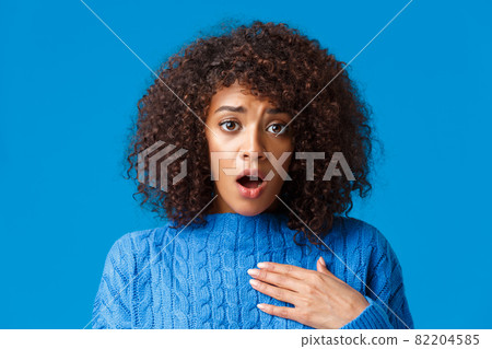 Concerned and worried shocked african-american woman pity for friend, heart bad news, touching heart and sighing with troubled upset expression, feeling uneasy for person, blue background Concerned and worried shocked african-american woman pity for friend, heart bad news, touching heart and sighing with troubled upset expression, feeling uneasy for person, blue background 82204585
