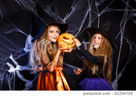 Two little kids in witch costumes having fun on Halloween 82204784