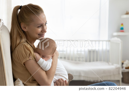 Happy young new mom holding sleepy baby in arms 82204946