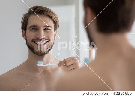 Handsome smiling shirtless man holding toothbrush with toothpaste Handsome smiling shirtless man holding toothbrush with toothpaste 82205699