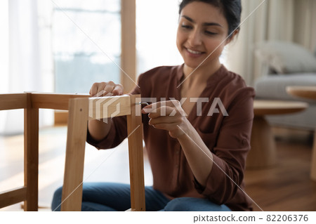 Happy young indian woman enjoy easy mounting flat pack furniture Happy young indian woman enjoy easy mounting flat pack furniture 82206376