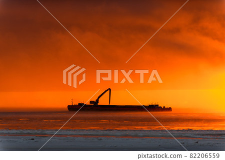 Beautiful sunset with fog in Arctic sea. Barge with excavator. 82206559
