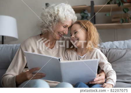 Happy old granny reading book with grandchild. Happy old granny reading book with grandchild. 82207075