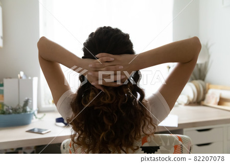 Woman relaxing on chair with hands behind head, rear view Woman relaxing on chair with hands behind head, rear view 82207078