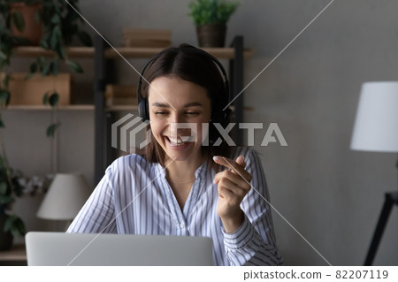 Close up excited woman in headphones engaged in video call 82207119