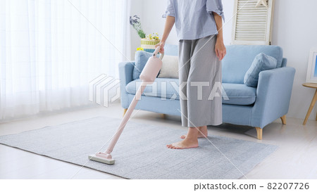 Young woman / housewife vacuuming the floor of the room Young woman / housewife vacuuming the floor of the room 82207726