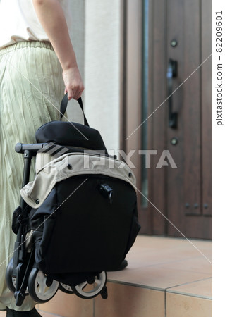 Housewife lifting a stroller and returning home Housewife lifting a stroller and returning home 82209601