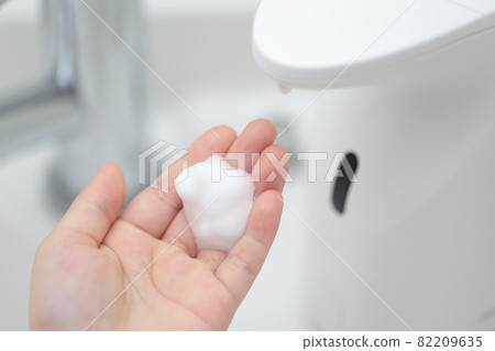 Girl washing hands with a hand soap dispenser on the wash basin 82209635