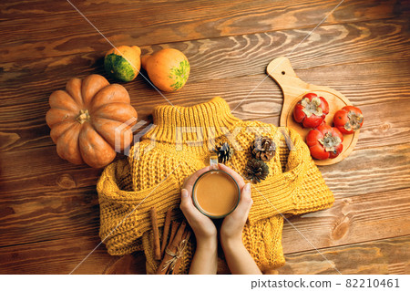 Cup of tea with milk, pine cones and cinnamon sticks on knitted sweater. Cup of tea with milk, pine cones and cinnamon sticks on knitted sweater. 82210461