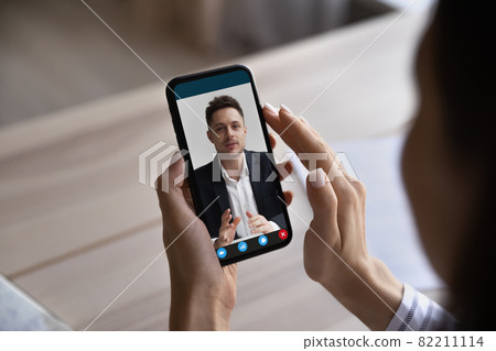 Close up woman holding smartphone, making video call to colleague 82211114
