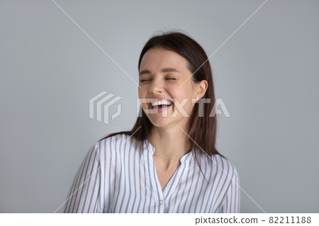 Head shot laughing excited young woman on grey background Head shot laughing excited young woman on grey background 82211188