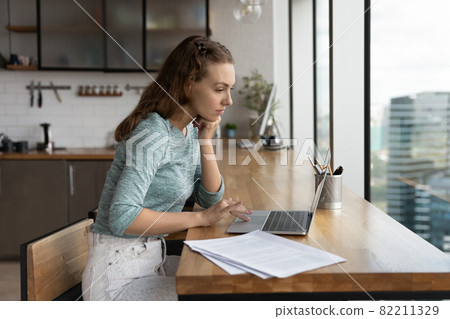 Pensive Caucasian woman work online on laptop 82211329