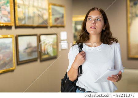 Thoughtful young girl in an art gallery studies works of art 82211375