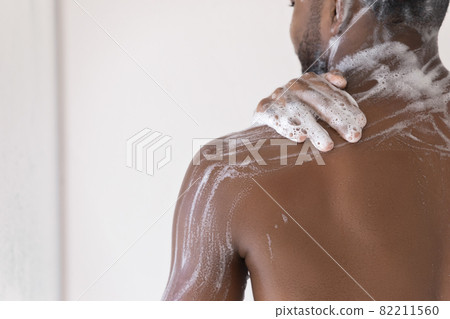 African man washes in shower, back and shoulder view African man washes in shower, back and shoulder view 82211560