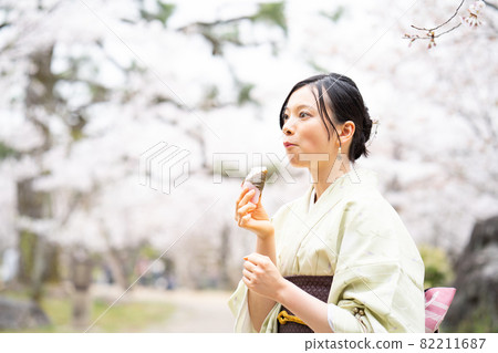 A woman sightseeing while eating sakura mochi deliciously 82211687