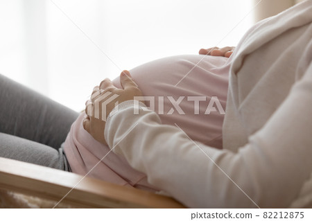 Closeup of young female expectant mother touch big baby bump Closeup of young female expectant mother touch big baby bump 82212875