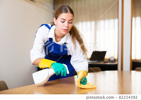 Portrait of a young female worker cleaning an office desk Portrait of a young female worker cleaning an office desk 82214392