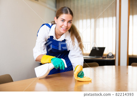Portrait of a young female worker cleaning an office desk Portrait of a young female worker cleaning an office desk 82214393