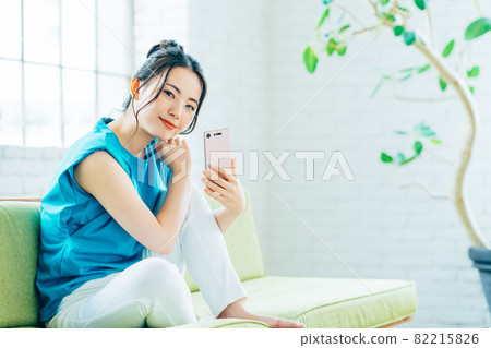 年輕女子在客廳看智慧型手機 年輕女子在客廳看智慧型手機 82215826