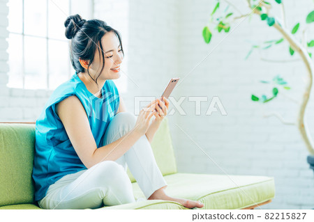 Young woman looking at her smartphone in the living room 82215827