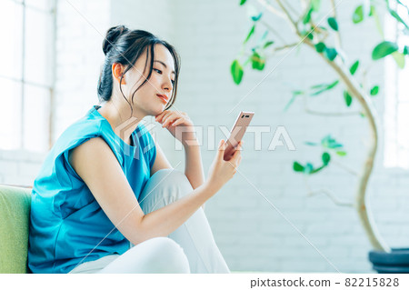 Young woman looking at her smartphone in the living room Young woman looking at her smartphone in the living room 82215828