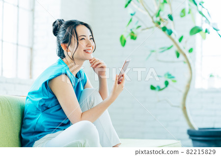 Young woman looking at her smartphone in the living room 82215829