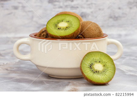 Kiwi fruits in porcelain bowl on the stone table 82215994